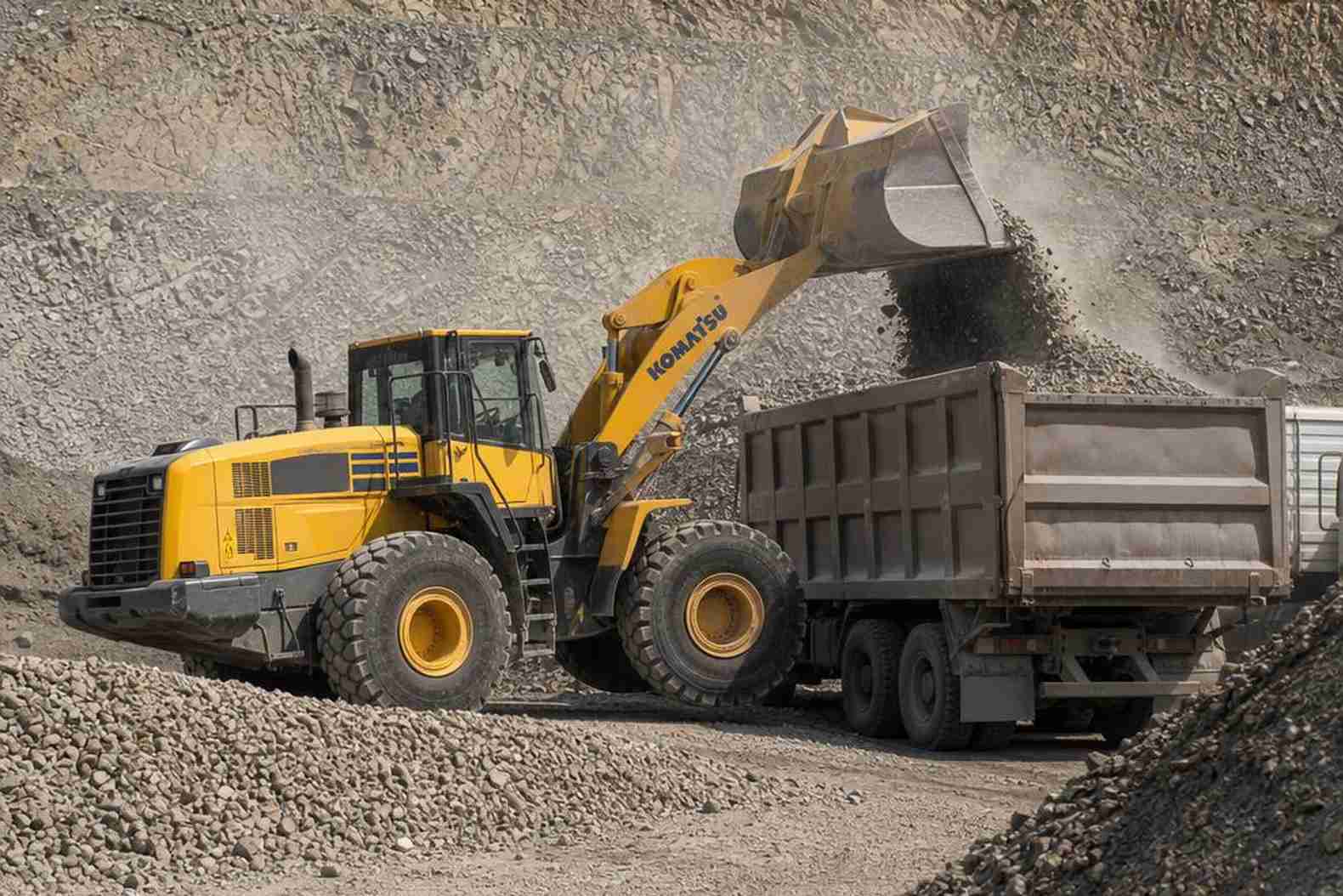 Фронтальный погрузчик Komatsu WA380 грузит щебень в самосвал