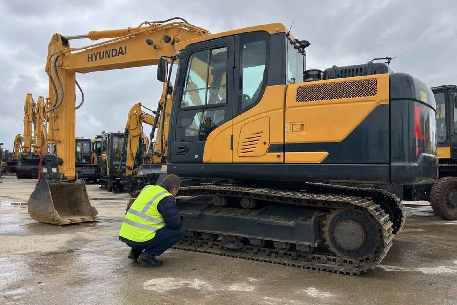 Экскаватор Hyundai R140 б/у осматривают перед покупкой на площадке дилера