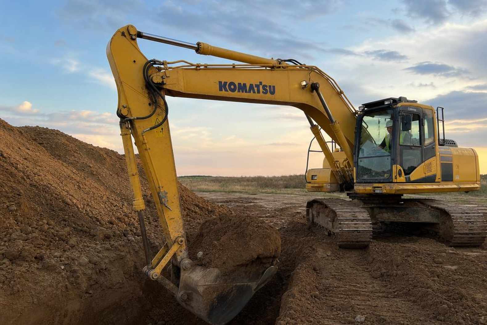Komatsu PC200-8 копает траншею в грунте средней плотности