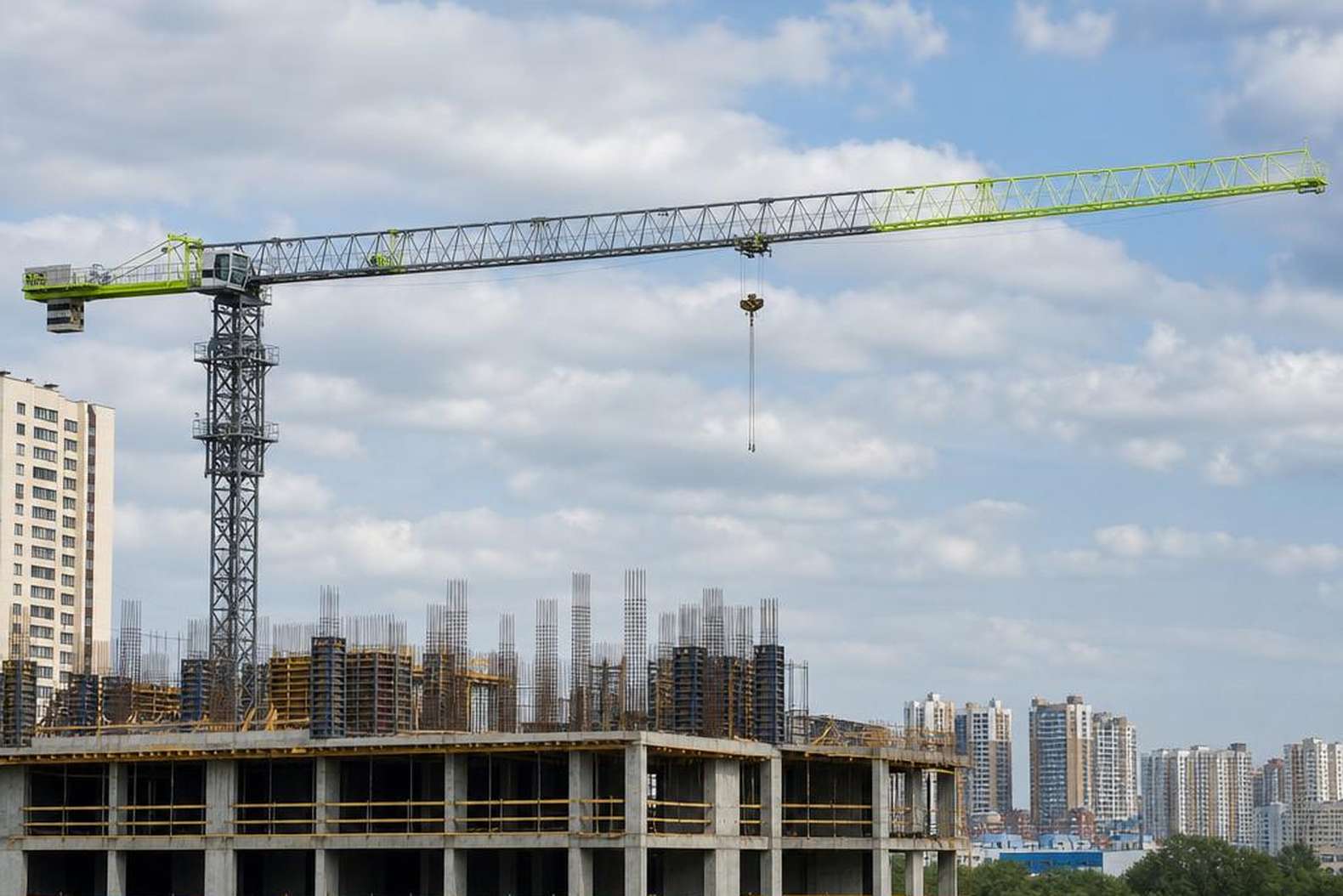 Стрела башенного крана TC5013 на вылете 50 метров над стройкой