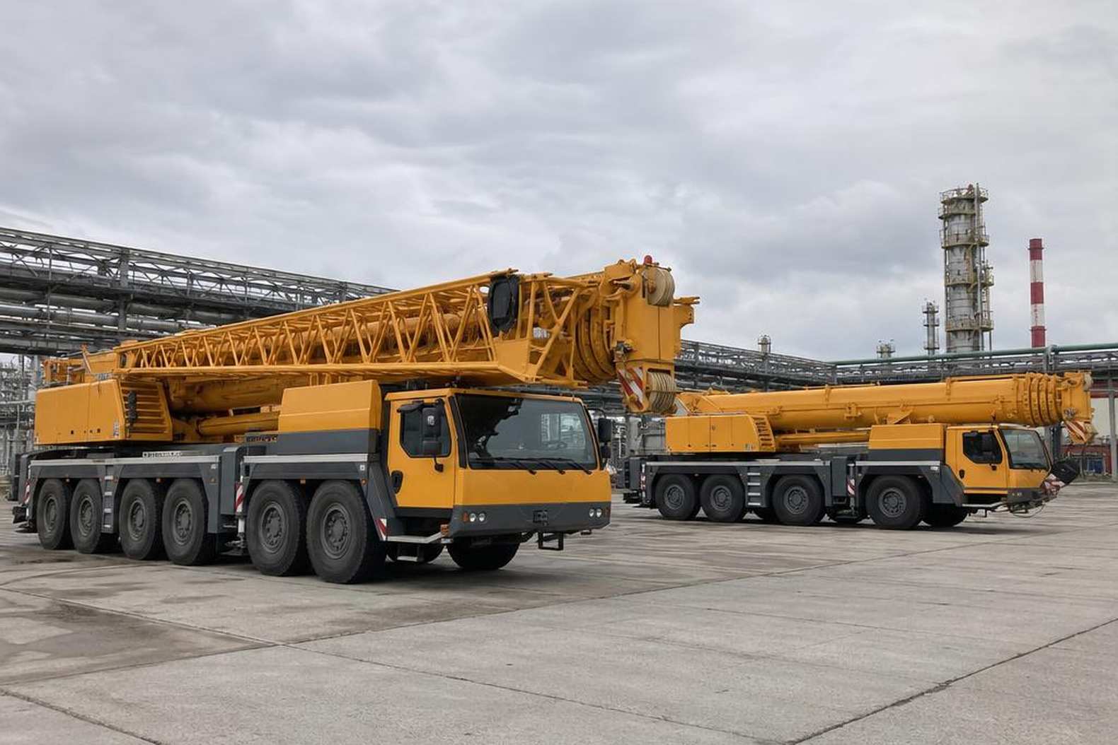 автокраны 50-тонного класса стоят на открытой площадке перед объектом